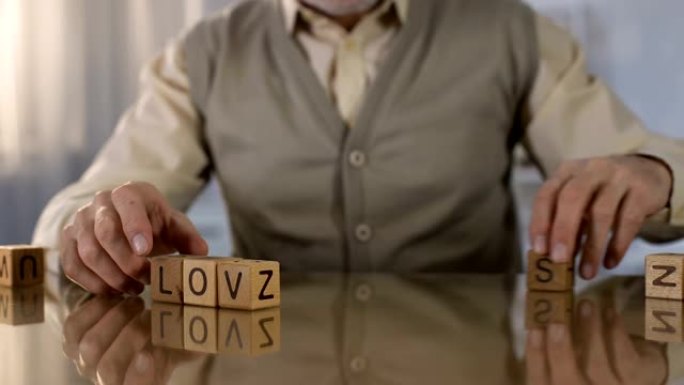 资深男子在桌上制作木制立方体的字爱，记忆疾病，健康