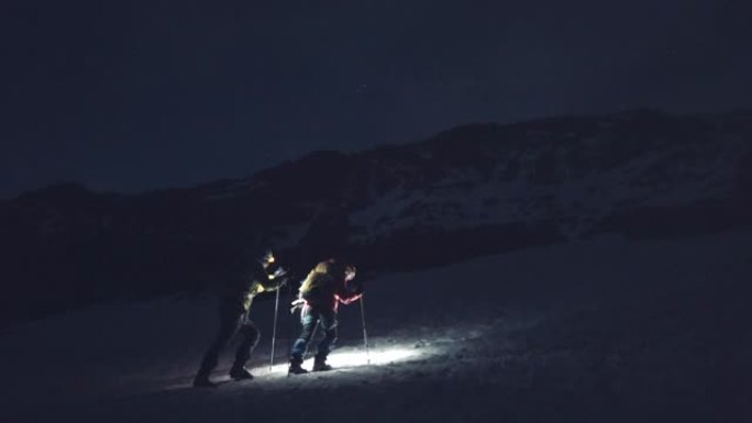 母女登山者在黎明时爬上雪山山脊