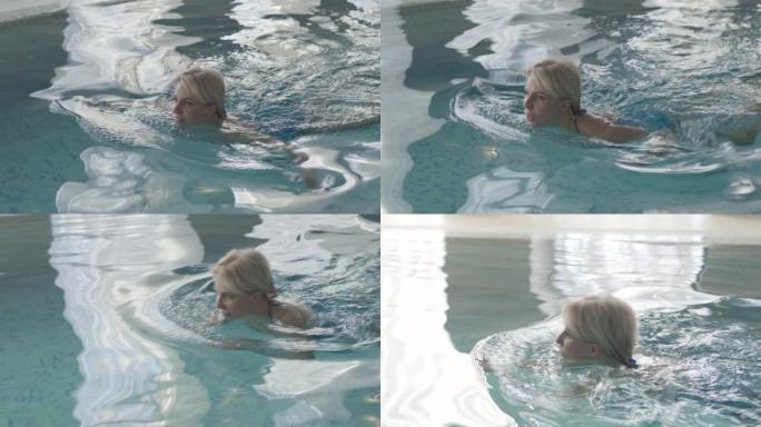 阳光明媚的日子，金发碧眼的白人妇女在室内盆上游泳的特写俯视图。自信的年轻女士在游泳池休息的肖像。休闲