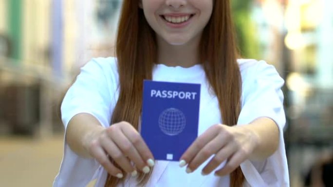 微笑的年轻女子出示蓝色护照，国际旅行证件，旅行