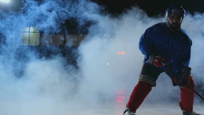 在冰场上有冰球的男曲棍球运动员展示了运球直接进入摄像机，并在烟雾中黑暗的背景下直接看着摄像机