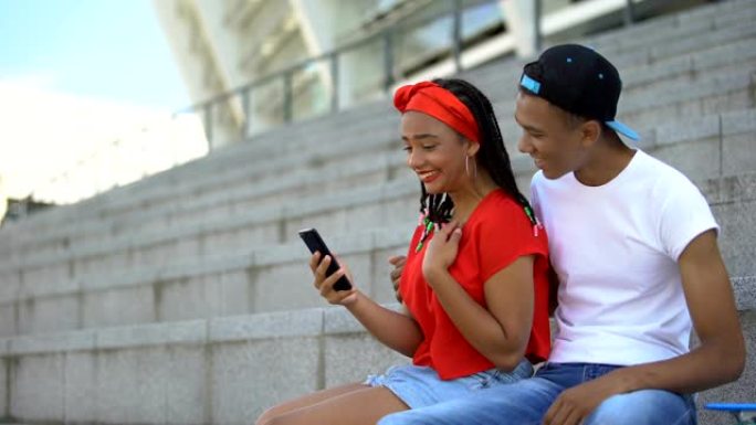 年轻夫妇微笑着看视频或在电话上阅读社交网络中的帖子