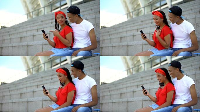 年轻夫妇微笑着看视频或在电话上阅读社交网络中的帖子