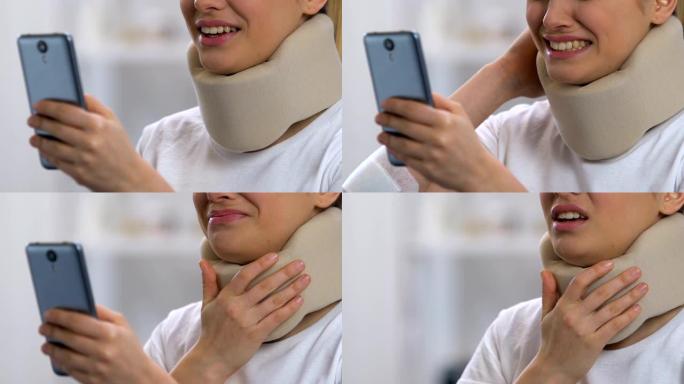 激动的女人在颈项圈拿着智能手机，感觉颈部剧烈疼痛
