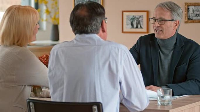 男建筑师在家里与一对高级夫妇握手