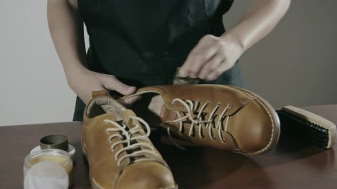 女鞋擦亮者用刷子擦亮棕色皮革的靴子