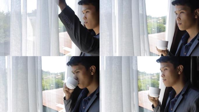 亚洲男子望着窗外喝茶
