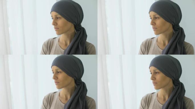 戴着头巾的沮丧女人看着窗户，康复中心，致命疾病
