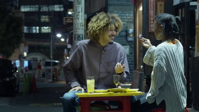 年轻女子在东京的户外餐厅向男友喂食食物
