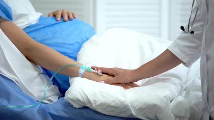 医生用导管握住孕妇的手，预防出生缺陷