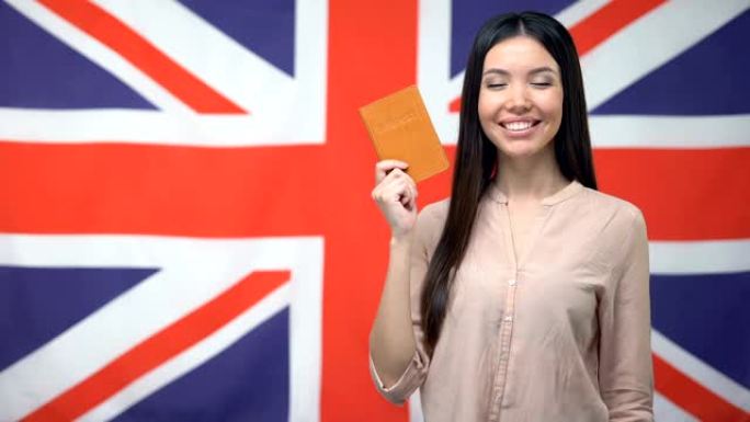 微笑的亚洲女孩拿着护照，带有英国国旗背景，公民身份