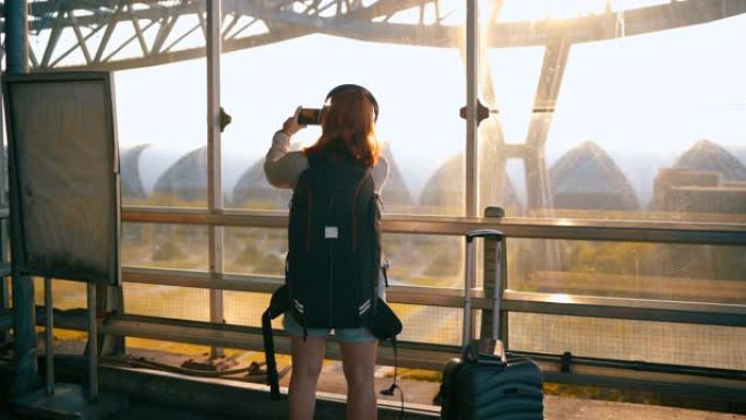4k镜头乘客通过拍摄日落照片等待航班飞行。机场外