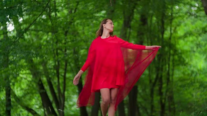 穿着红色连衣裙的女人在森林里旋转