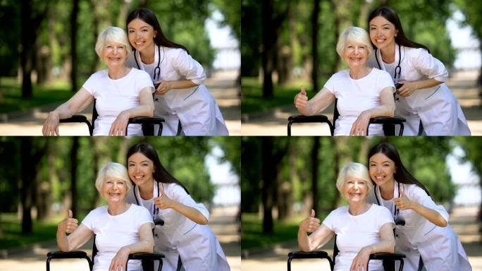 护士和老残障妇女对着镜头微笑，并表现出竖起大拇指的手势