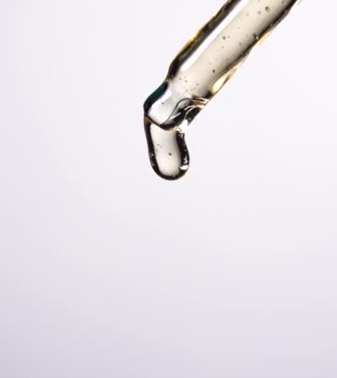 垂直射击: 油滴从白色背景的移液器上掉落