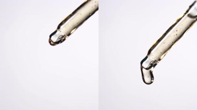 垂直射击: 油滴从白色背景的移液器上掉落