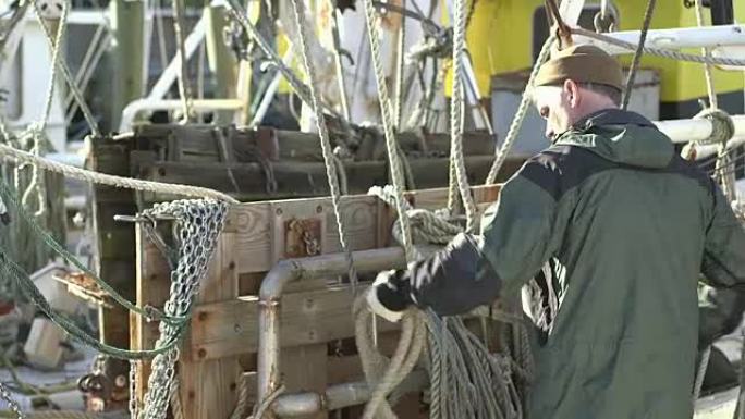 男子在商业渔船上盘绕绳索
