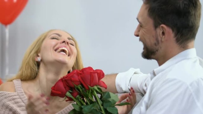有爱心的男人向他美丽的女人献上一束玫瑰花感到惊讶