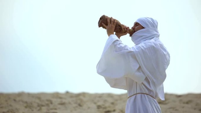 干渴的阿拉伯朝圣者从沙漠中的瓶子喝水，干旱问题