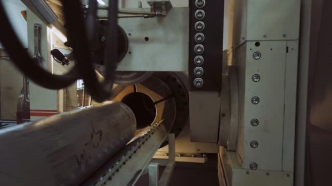 三十多岁的高加索技术人员将钢管滑入室内制造厂的旋转成型机末端的位置
