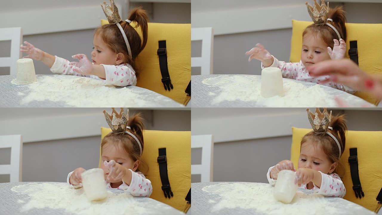 可爱的女婴在桌子上玩面粉，戴着皇冠
