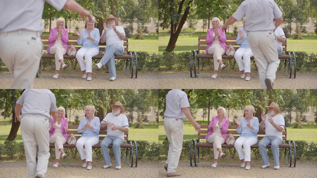 三名高加索老人坐在长凳上，为他们开朗的男性朋友跳舞鼓掌