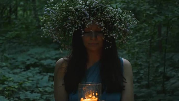 美丽的女孩在森林里拿着燃烧的蜡烛