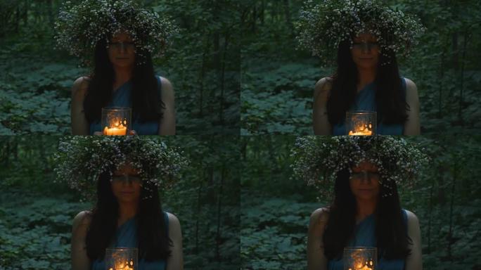 美丽的女孩在森林里拿着燃烧的蜡烛