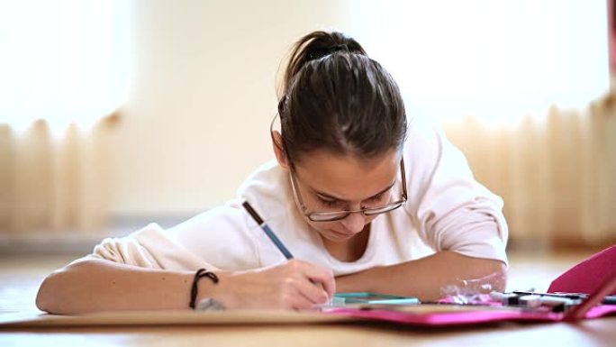 十几岁的女孩在学校做作业，躺在客厅的地板上