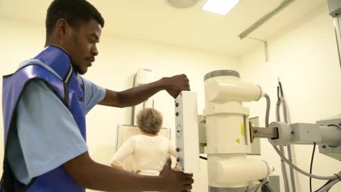 男性黑人放射科医生在医院准备进行胸部x光检查时调整x光机