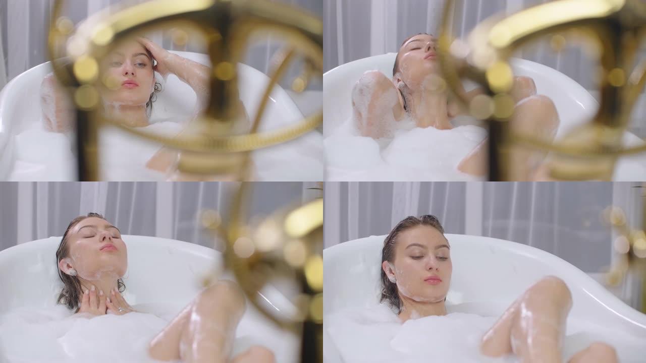 美丽的女人躺在浴缸里享受泡泡浴。美容、休闲、保健理念