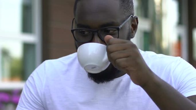 微笑的非裔美国人喝咖啡并在社交网络中聊天