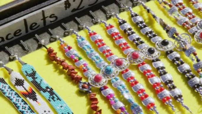 多色美洲原住民风格 (纳瓦霍) 珠宝 (戒指，手镯和耳环) 的特写平移照片，在阳光明媚的日子里以价格