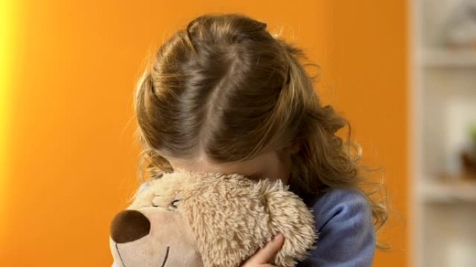 可爱的害羞学龄前女孩在泰迪熊藏脸，童年心理学