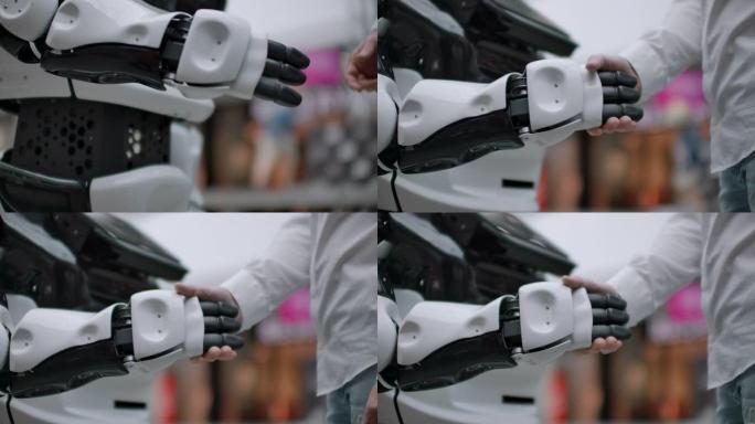 现代机器人技术。一个人与机器人交流，将塑料机械臂压在机器人上，握手