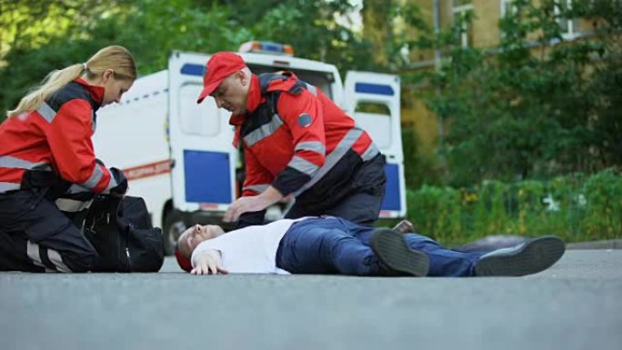 救护人员跑向躺在道路上的男子，在车祸现场急救