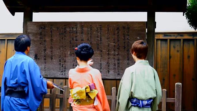 四个穿着和服的日本人观看布告板