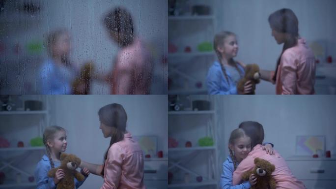 母亲用泰迪熊安抚小女孩，从噩梦中醒来，拥抱