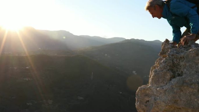 男性徒步旅行者在日出时达到悬崖峰顶