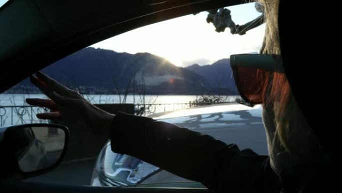 女人在日出时在汽车中放松，看着远处的场景
