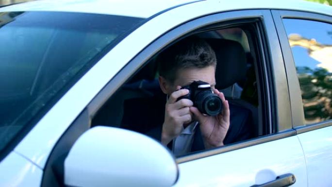 私家侦探从汽车上监视，在相机上拍照，调查