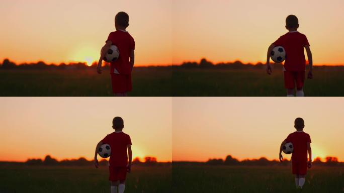 男孩足球运动员带球在球场上，夕阳摄像机跟着男孩。