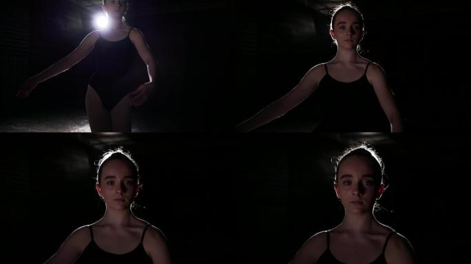 肖像可爱的芭蕾舞演员站在工作室黑色背景的聚光灯下。芭蕾舞女演员展示经典芭蕾舞剧。慢动作。