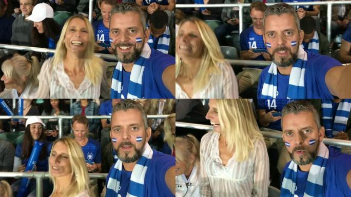 穿着足球迷服装的男子制作了他和女友在体育场欢呼的智能手机视频