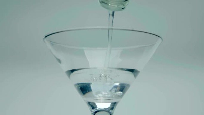 一名男子将伏特加酒 (酒精饮料) 从瓶子倒入玻璃杯中