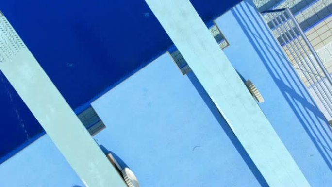 阳光普照的蓝色水池上方的CS跳水板