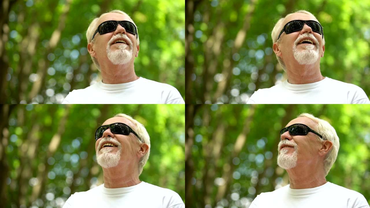 戴着墨镜的视障男子聆听自然声音，提高感官