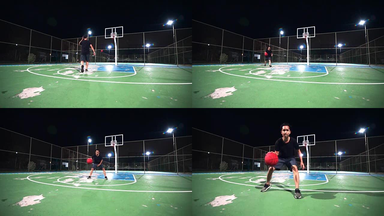 运动概念: 一个晚上独自在室外球场上打篮球的人。