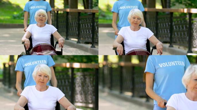 志愿者帮助轮椅上的老年女性患者在医院公园散步