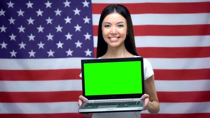 女人拿着带绿屏的笔记本电脑，背景上的美国国旗，语言课程